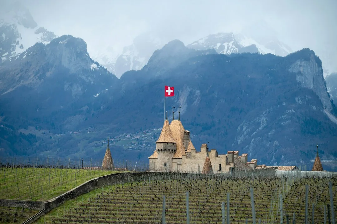 Burg mit Schweizer Fahne vor verschneiten Bergen